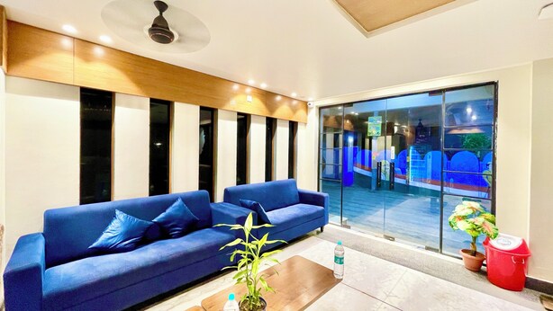 A modern living room with a blue sofa, a wooden coffee table, and a potted plant. - RB INTERNATIONAL - PURI near Sea Beach (Puri)