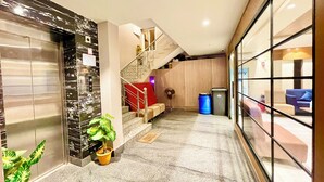 A modern hotel lobby with a marble floor, a staircase, a reception desk, and a large window offering a view of the interior. - RB INTERNATIONAL - PURI near Sea Beach (Puri)