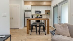 Une cuisine moderne avec des meubles blancs, une table en bois et des tabourets de bar noirs.