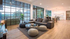 Un salón amplio con un sofá moderno, una mesa de centro de cristal y un comedor con una cocina al fondo.