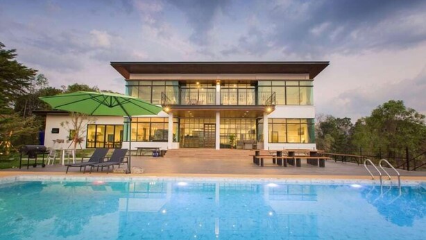 Un edificio moderno de dos pisos con una piscina delantera.