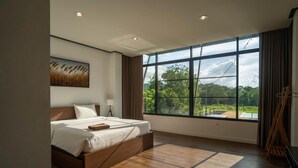 Habitación de hotel moderna con una cama grande, un cuadro en la pared y vistas a zonas verdes.
