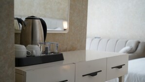 A hotel room with a white dresser, a coffee maker, and a bed with white bedding. - Sword Suit Hotel (Istanbul)