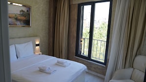 A hotel room with a large bed, a chair, a window with a view, and a painting on the wall. - Sword Suit Hotel (Istanbul)