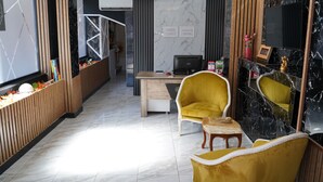 A modern hotel lobby with a reception desk, a flat-screen TV, and yellow armchairs. - Sword Suit Hotel (Istanbul)