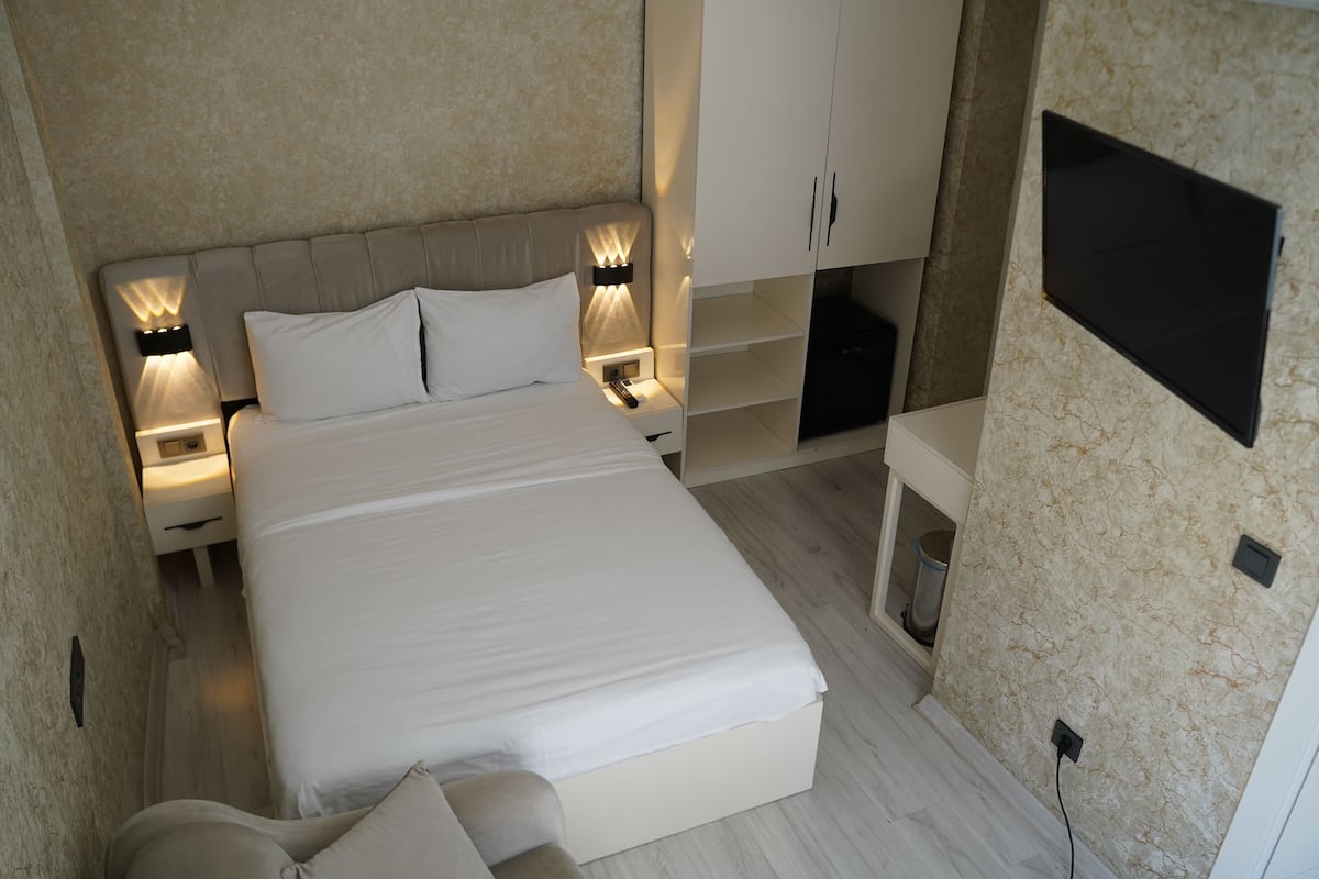 Un dormitorio moderno con una cama grande, lámparas de noche, un televisor montado en la pared y estanterías empotradas.