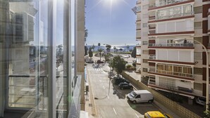 A multi-story building with balconies and a view of a street with parked cars and palm trees. - A&N California (Torre del Mar)