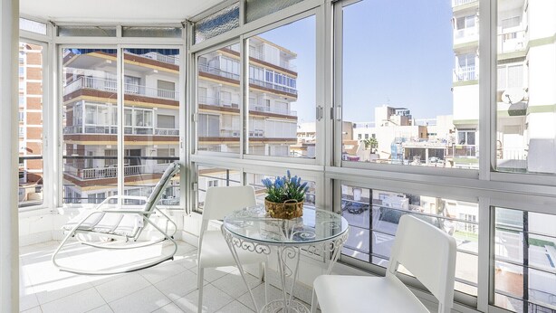 A balcony with a glass table, white chairs, and a rocking chair. - A&N California (Torre del Mar)