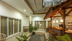 A spacious indoor area with a bar, seating, and potted plants. - Kubu Ramah Canggu (Tibubeneng)