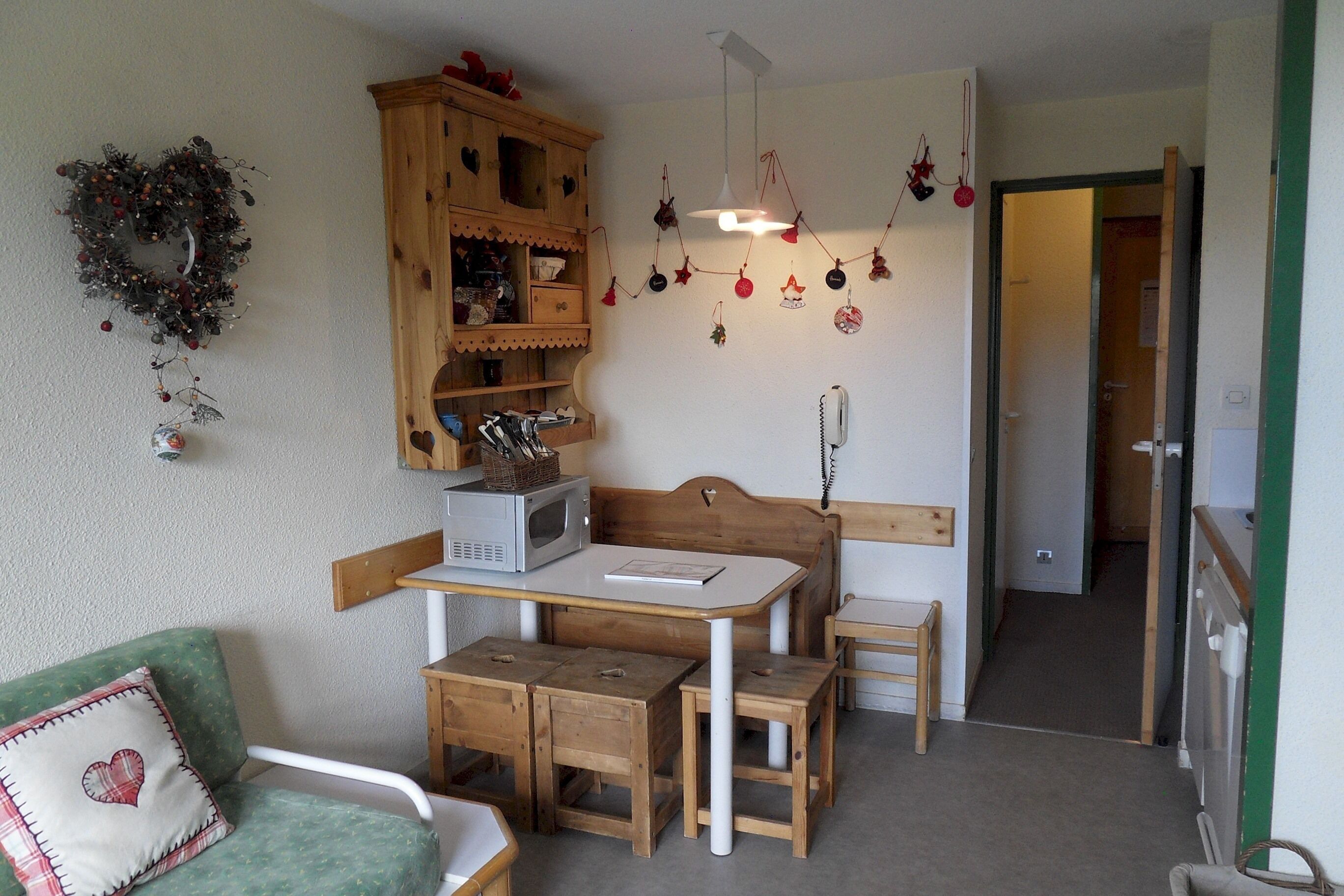 A cozy kitchen with wooden furniture, a microwave, and a telephone.