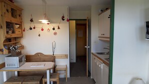 Una cocina compacta con una mesa de madera, un microondas y una lámpara colgante.