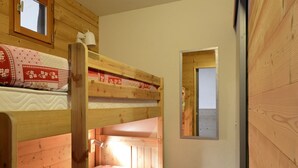 A bunk bed room with wooden walls and a small window. - travelski home select - Vue Pistes - Studio cabine 3/4 personnes Etoile F16 (La Plagne)