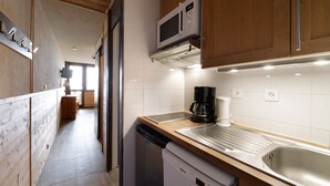 A compact kitchen with a microwave, coffee maker, and dishwasher. - travelski home select - Vue Pistes - Studio cabine 3/4 personnes Etoile F16 (La Plagne)