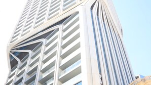 A modern high-rise building with a unique architectural design featuring curved lines and large windows. - Luxury High Floor Suite Mercury Towers (St. Julian's)