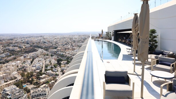 A rooftop pool area with a city view, lounge chairs, and umbrellas. - Luxury High Floor Suite Mercury Towers (St. Julian's)