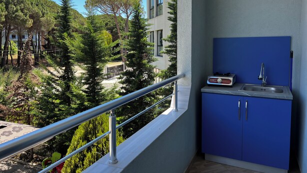 A balcony with a blue cabinet, a sink, and a stove. - Canary Hotel (Golem)