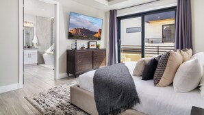 A modern bedroom with a large bed, a flat-screen TV, a dresser, and a balcony with a railing. - Pecan Valley Paradise  (Hurricane)