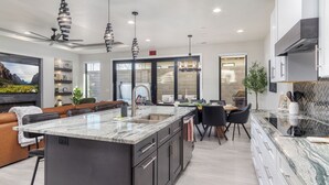 A modern kitchen with a central island, dark cabinetry, and pendant lighting. - Pecan Valley Paradise  (Hurricane)
