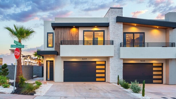 A modern two-story house with a garage, a balcony, and a stop sign nearby. - Pecan Valley Paradise (Hurricane)
