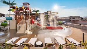 A water park area with slides, a water fountain, and lounge chairs. - Pecan Valley Paradise  (Hurricane)