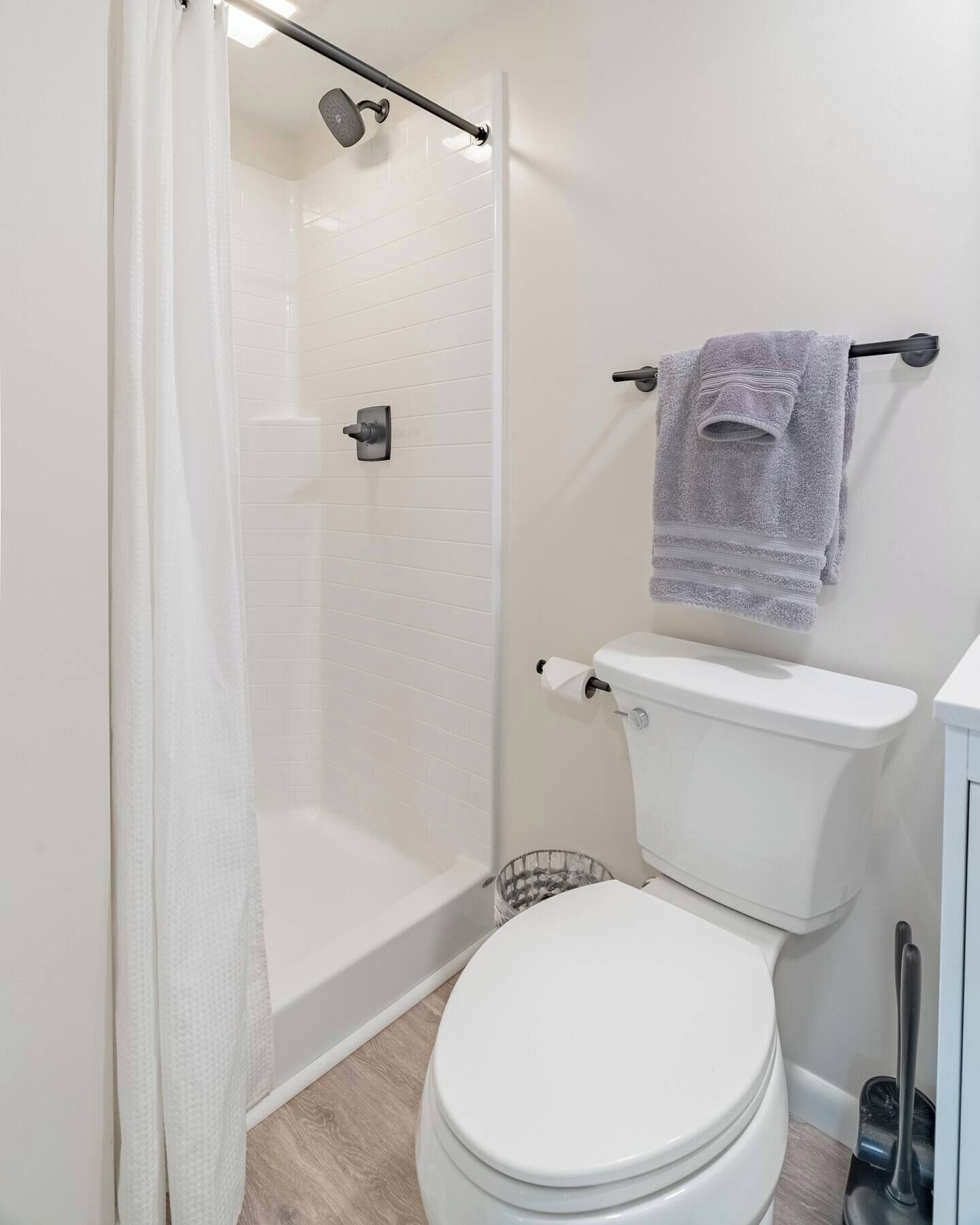 A modern bathroom with a shower, toilet, and towel rack.