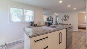 A modern kitchen with granite countertops, a built-in dishwasher, and a window with blinds. - This house is a 3 bedroom(s), 2 bathrooms, located in Marion, IN. (Marion)