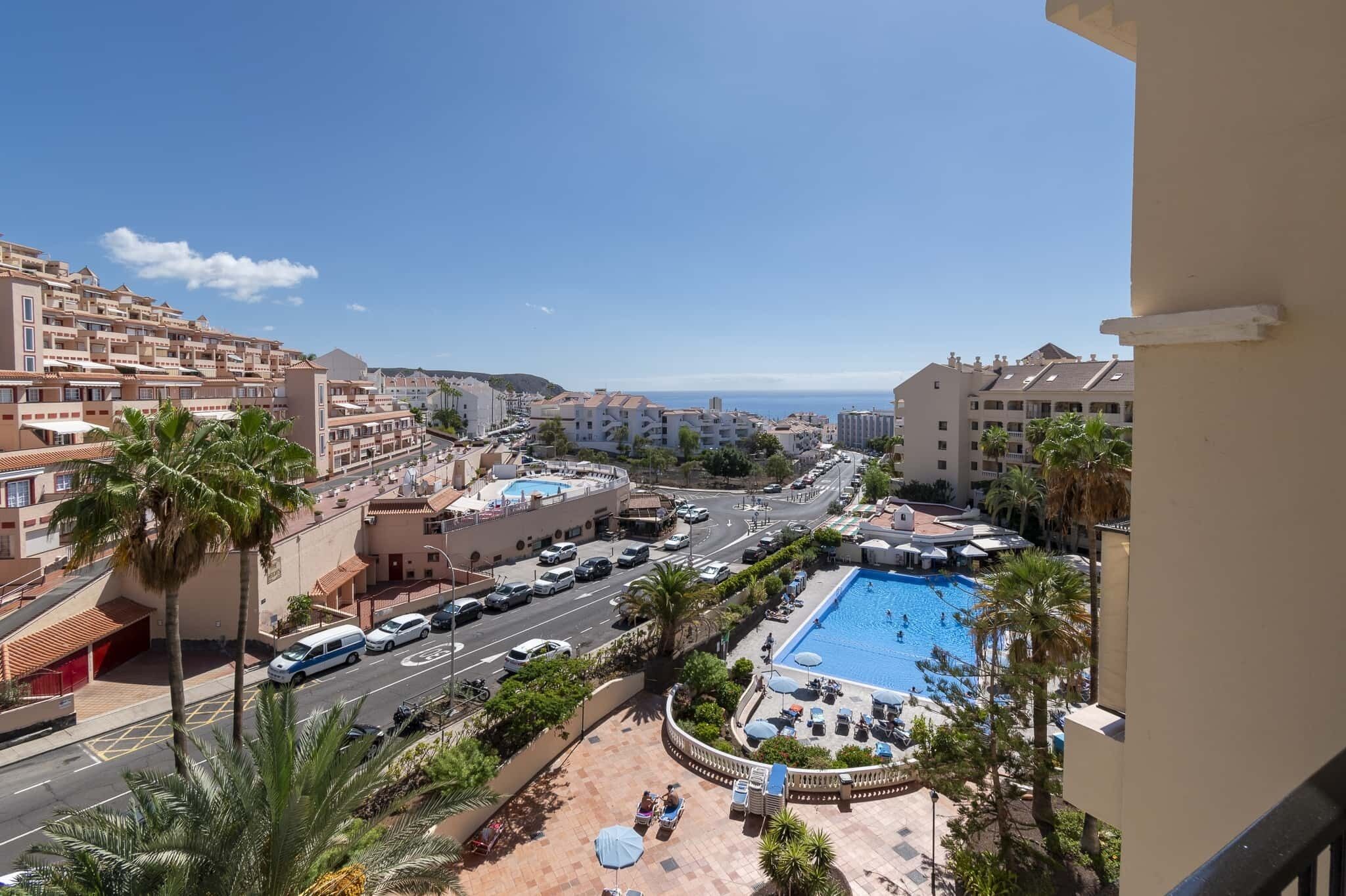 A resort with a swimming pool, palm trees, and a view of the city.