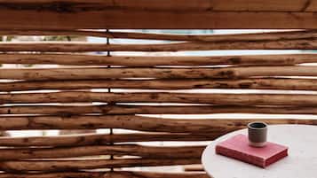 A wicker chair and a small round table with a book and a cup.
