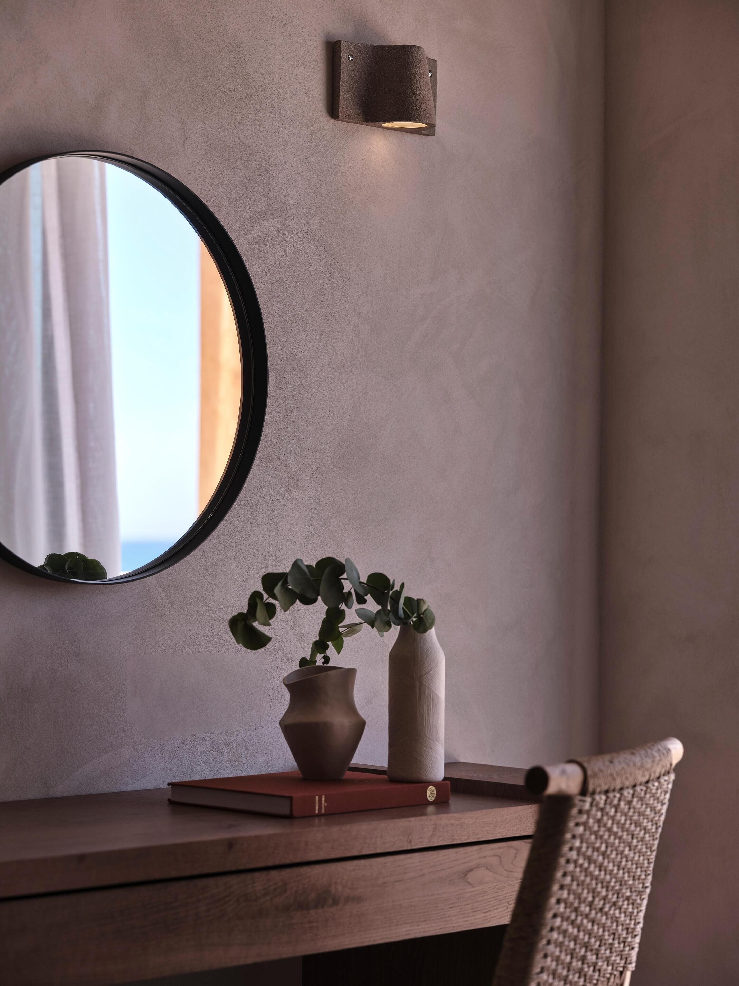 A wooden desk with a mirror, a potted plant, and a vase.