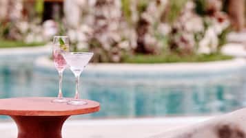 Una mesa junto a la piscina con dos vasos de agua y hojas de menta.