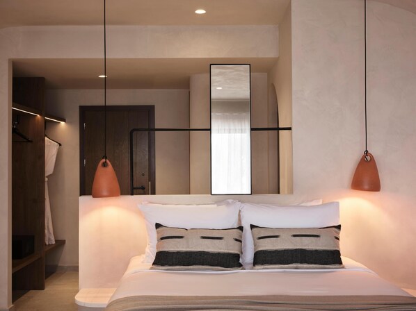 Un dormitorio moderno con cama, lámparas de noche, un armario y un espejo.