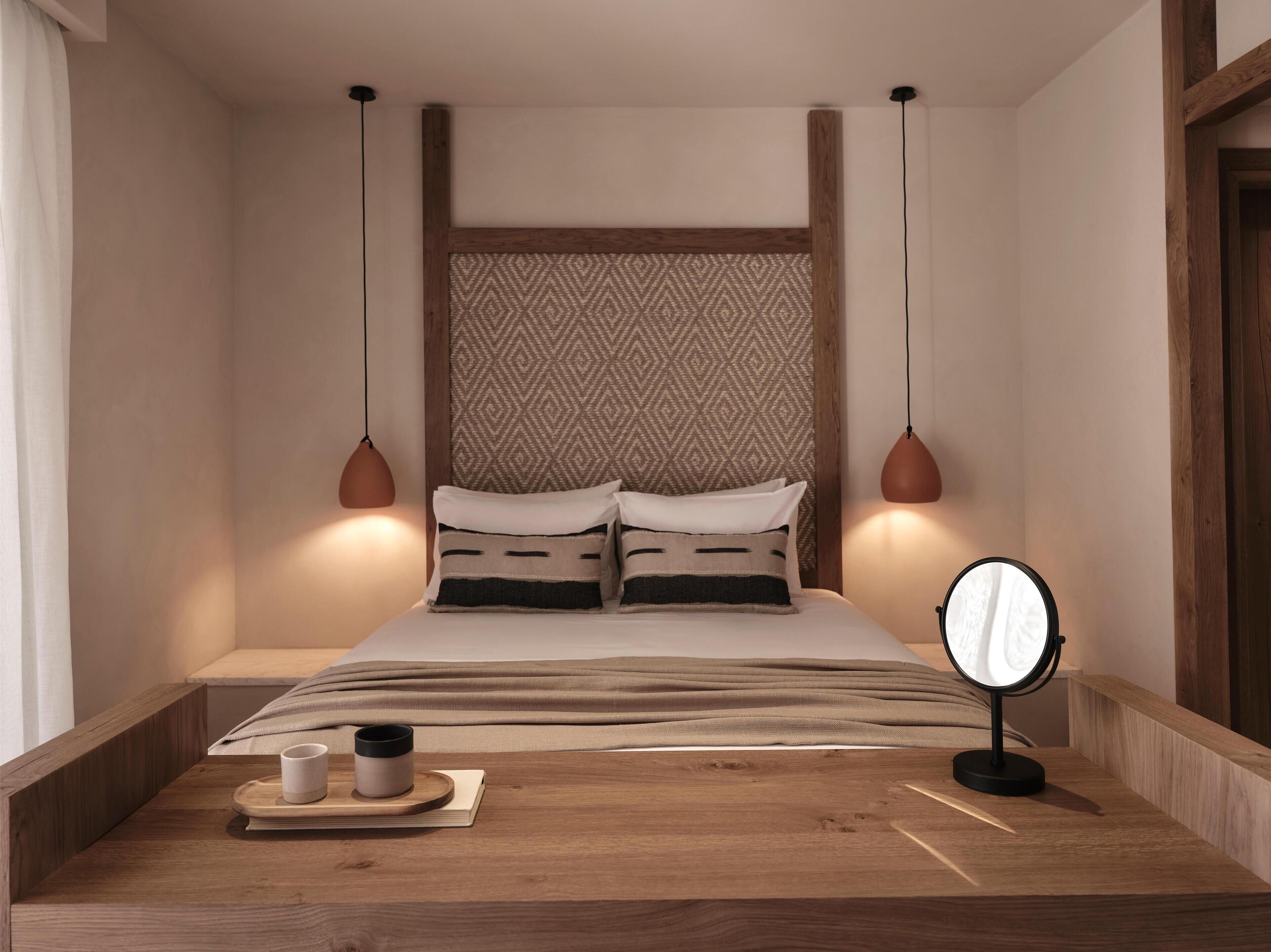 Ein ordentlich eingerichtetes Schlafzimmer mit Bett, Nachttisch und Spiegel.