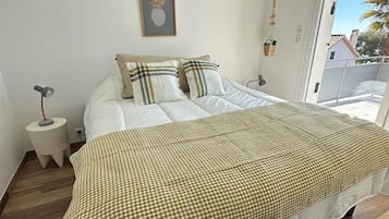 Ein Schlafzimmer mit einem großen Bett, einem kleinen Nachttisch, einer gerahmten Ananas-Kunst und Blick ins Freie.