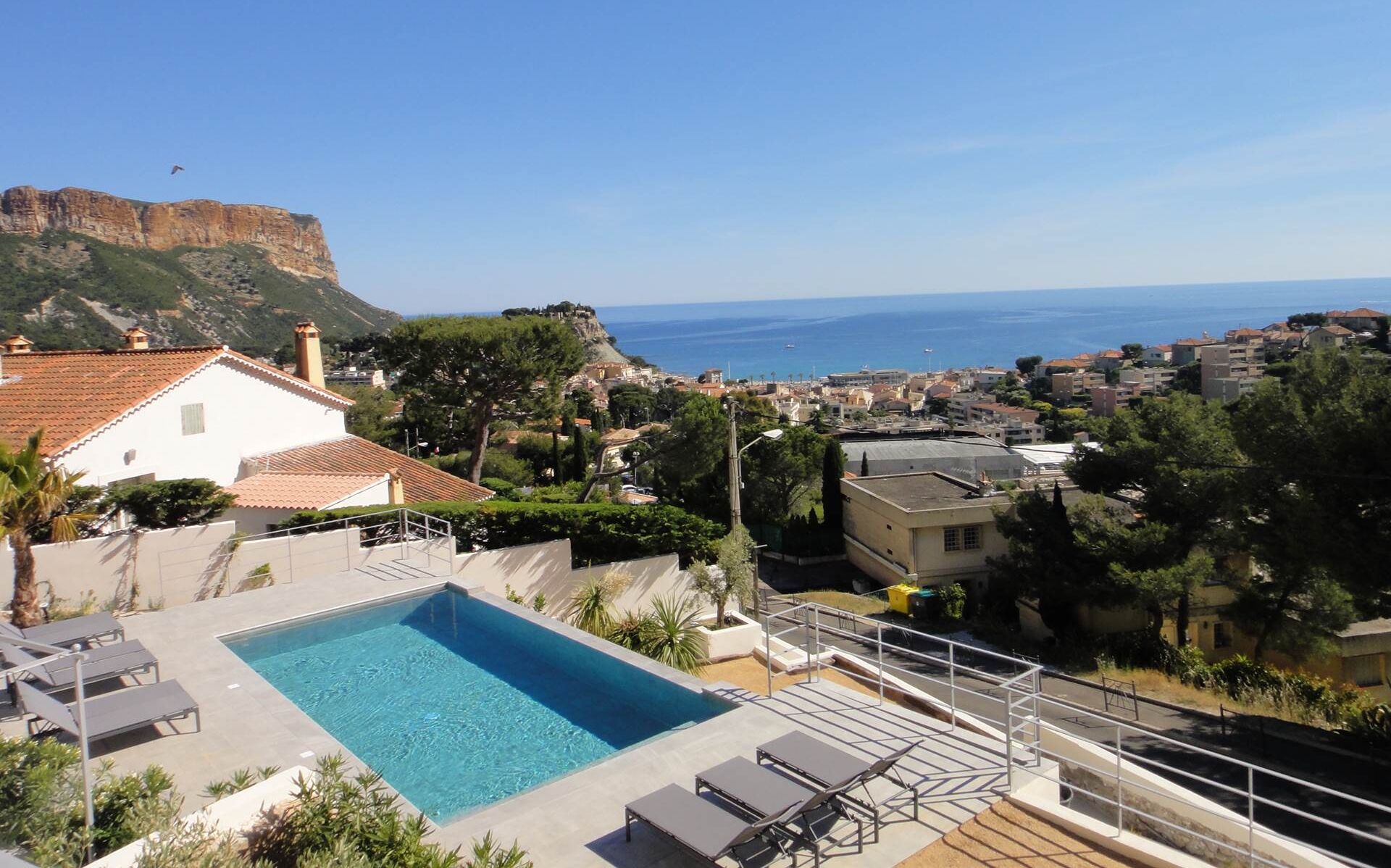 A rooftop pool with a clear view of the sea and a mountainous backdrop.