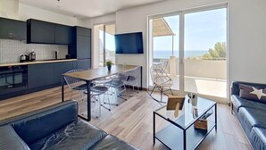 A modern living space with a kitchen, dining area, and a balcony with a view.