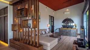 A modern living room with a sectional sofa, wooden shelving, and a dining area with a large island.