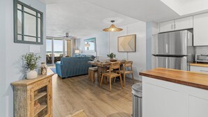 Una cocina moderna con refrigerador de acero inoxidable, mesa de comedor de madera y armarios blancos.