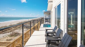 A balcony with a view of the beach, a pool, and outdoor seating. - Oceanfront Beach House, Elevator to First Floor, Ocean View Pool, Dog Friendly (Pawleys Island)