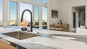 A modern kitchen with a large window, a marble countertop, and a sink. - The Tree House By The Cohost Company (Joshua Tree)