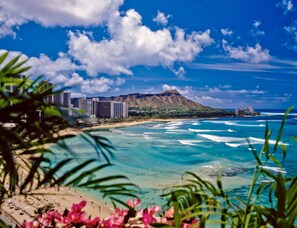 A coastal view with a beach, ocean waves, and a mountain in the background. - Waikiki Sunset Close to Beach with Parking (Honolulu)