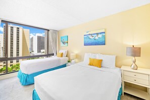 A hotel room with two beds, a large window with a city view, and artwork on the walls. - Waikiki Sunset Close to Beach with Parking (Honolulu)