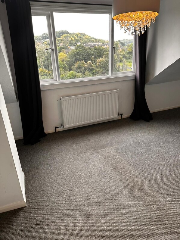 A room with a large window, a radiator, and a chandelier.