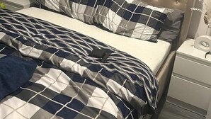 A bed with a tufted headboard, a checkered bedspread, and a bedside table with a lamp. - Chatham Retreat by the River (Chatham)