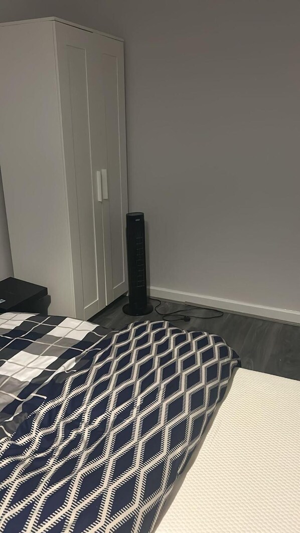 A bedroom with a bed, a wardrobe, and a standing heater.