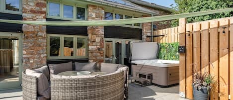 Ein Patio mit Korbmöbeln, einem Whirlpool und einem Holzzaun.