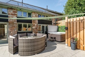 Un espacio al aire libre con mobiliario de mimbre, un jacuzzi y una valla de madera.