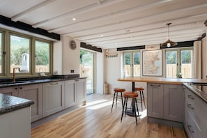 Una cocina con encimera de madera, armarios grises y un ventanal grande.