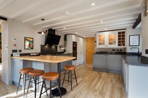 Una cocina moderna con una isla central, taburetes de bar y un ventanal amplio.