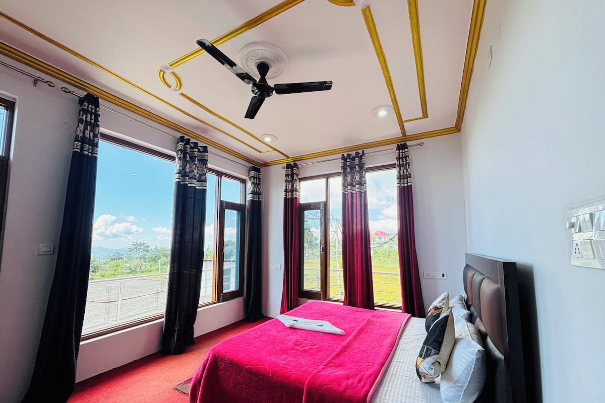 A bedroom with a bed, a ceiling fan, and large windows with curtains.