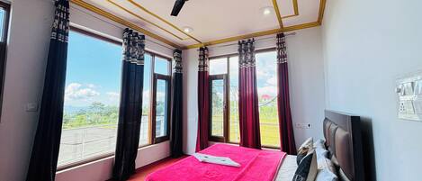 A bedroom with a bed, a ceiling fan, and large windows with curtains.